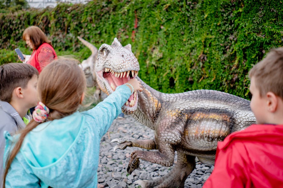 children looking at dinosaur statues