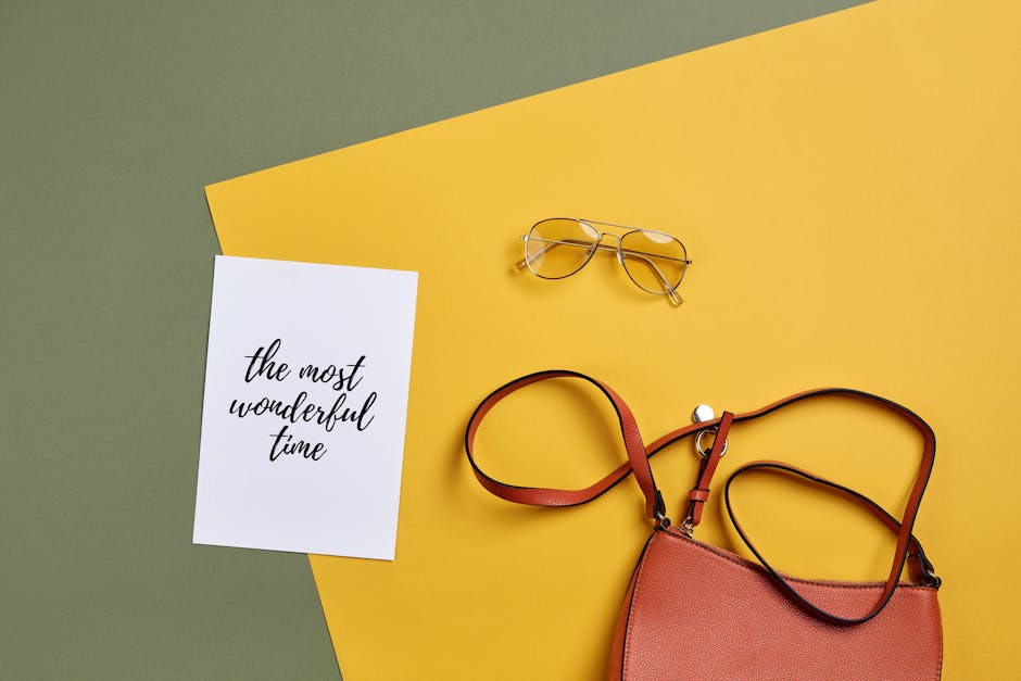 flat lay of minimalist accessories like watch, simple jewelry, and leather bag
