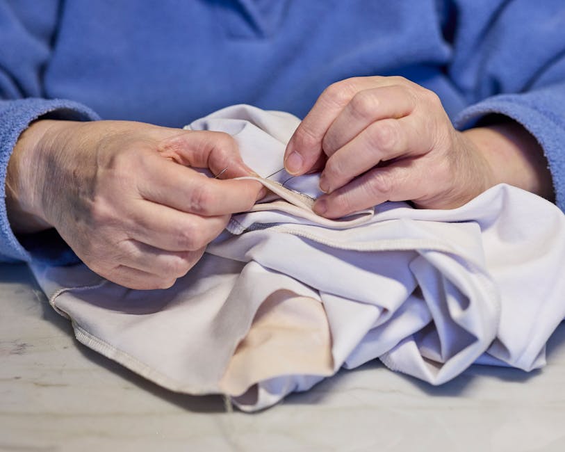 hands mending fabric with needle and thread