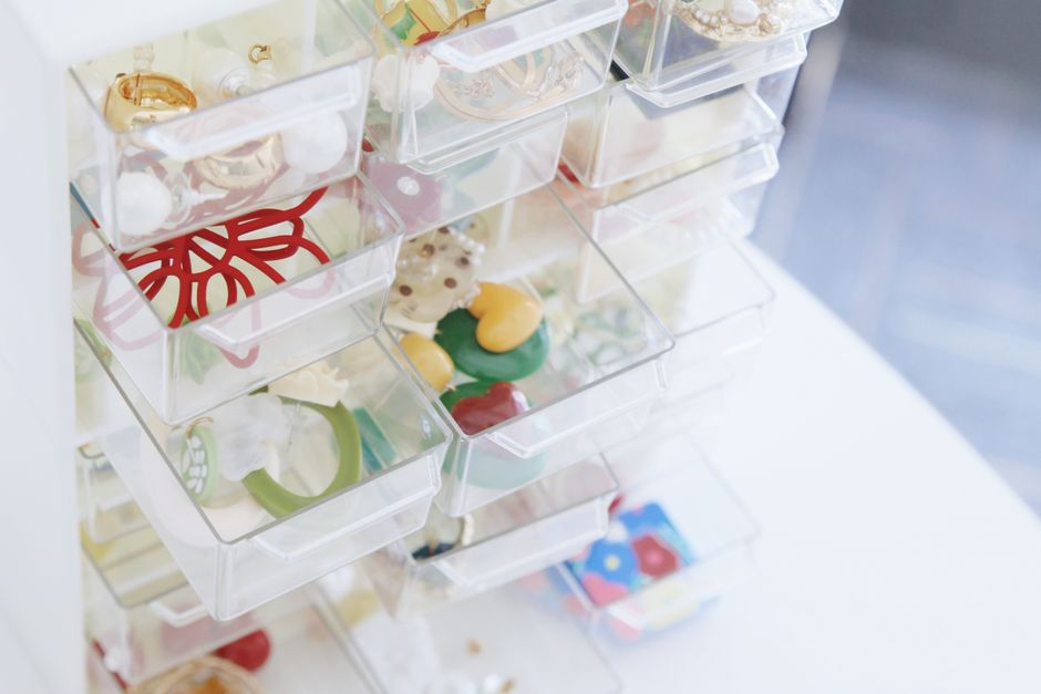 A clear multi-tiered acrylic organizer filled with various lipsticks, foundations, and eyeshadow palettes on a clean bathroom counter, highlighting accessibility.