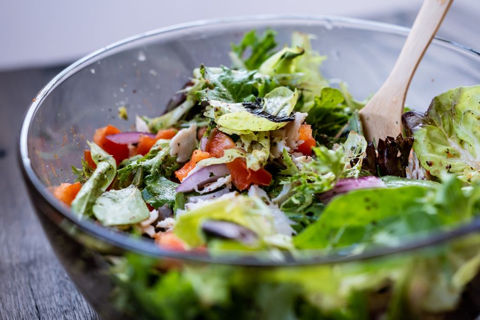 A vibrant, colorful no-cook salad bowl filled with fresh greens, cherry tomatoes, cucumber, chickpeas, feta, and olives, with a light vinaigrette.
