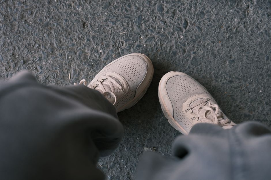 Person walking briskly through a European city street, wearing comfortable yet stylish black walking shoes, carrying a work bag.