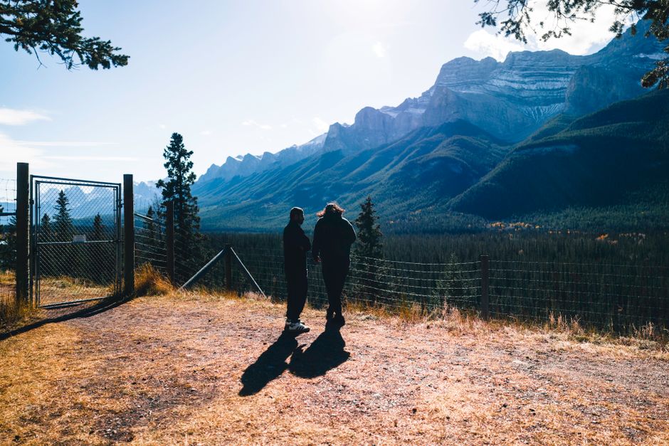 A couple hikes on a scenic trail in a national park during autumn, surrounded by vibrant fall foliage and clear skies, highlighting pleasant weather.