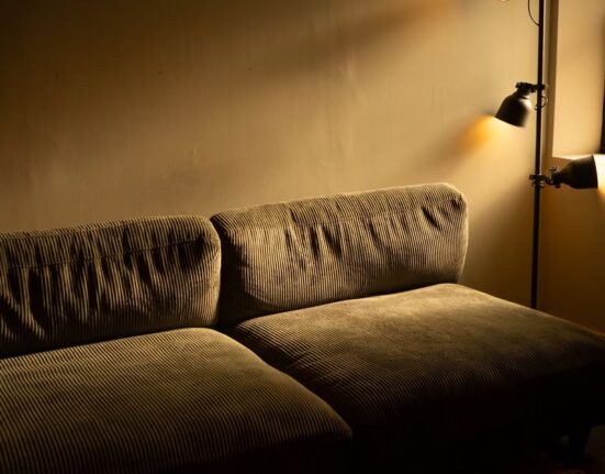 A cozy living room bathed in warm, adjustable smart lighting, showing a mix of floor and table lamps, enhancing comfort.