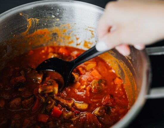 A steaming, rich beef and vegetable stew in a large Dutch oven on a rustic wooden table, with cozy lighting and a warm ambiance.