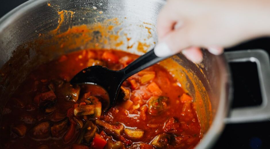 A steaming, rich beef and vegetable stew in a large Dutch oven on a rustic wooden table, with cozy lighting and a warm ambiance.