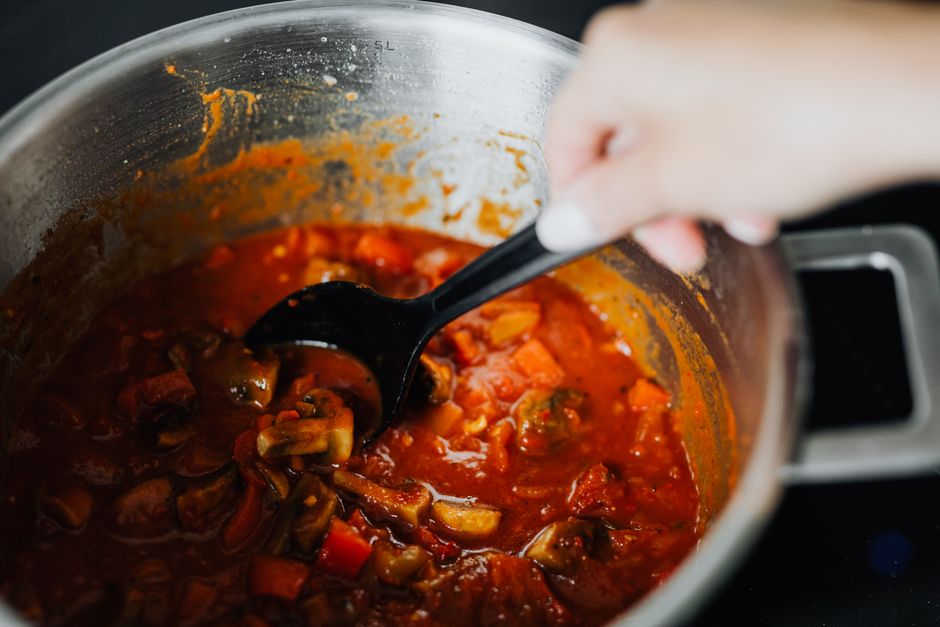 A steaming, rich beef and vegetable stew in a large Dutch oven on a rustic wooden table, with cozy lighting and a warm ambiance.