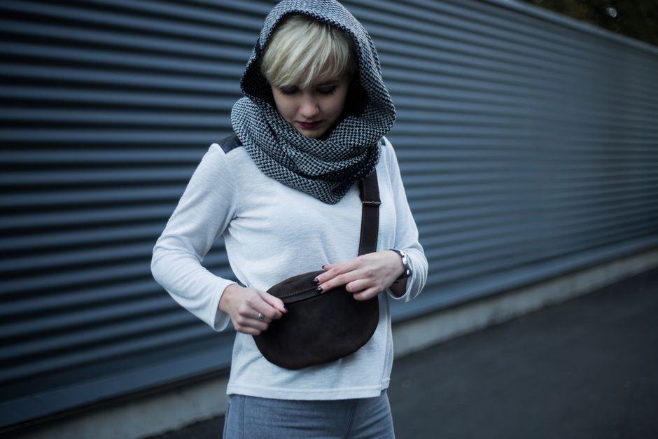 A woman confidently walking through a European city street, wearing a stylish crossbody bag with external zippers and pockets, indicating secure travel essentials.