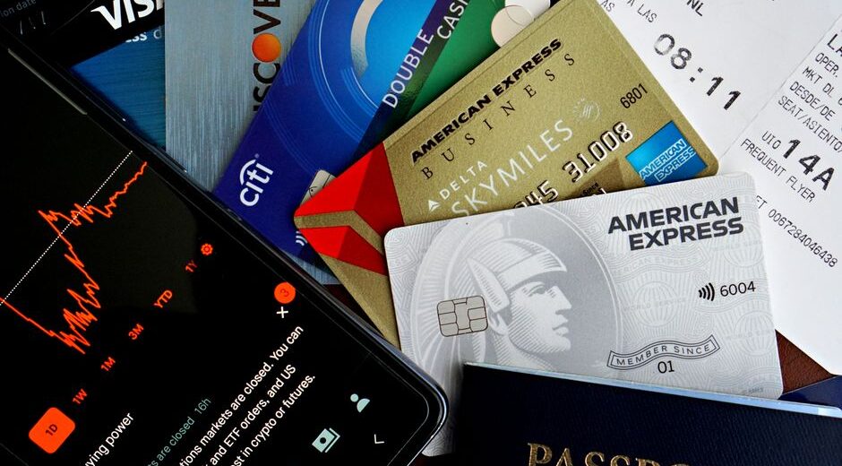 An assortment of credit and debit cards from different banks, with various international currency notes like Euros, Dollars, and Pounds scattered around them, symbolizing options for travel payments.