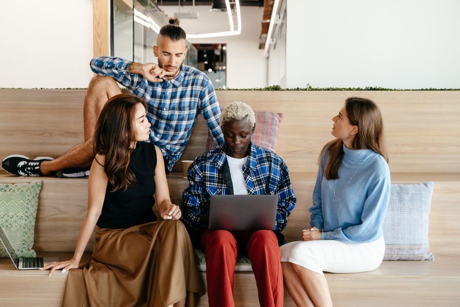 A group of friends or a couple gathered around a laptop, reviewing travel options and discussing itinerary changes, highlighting collaborative planning.