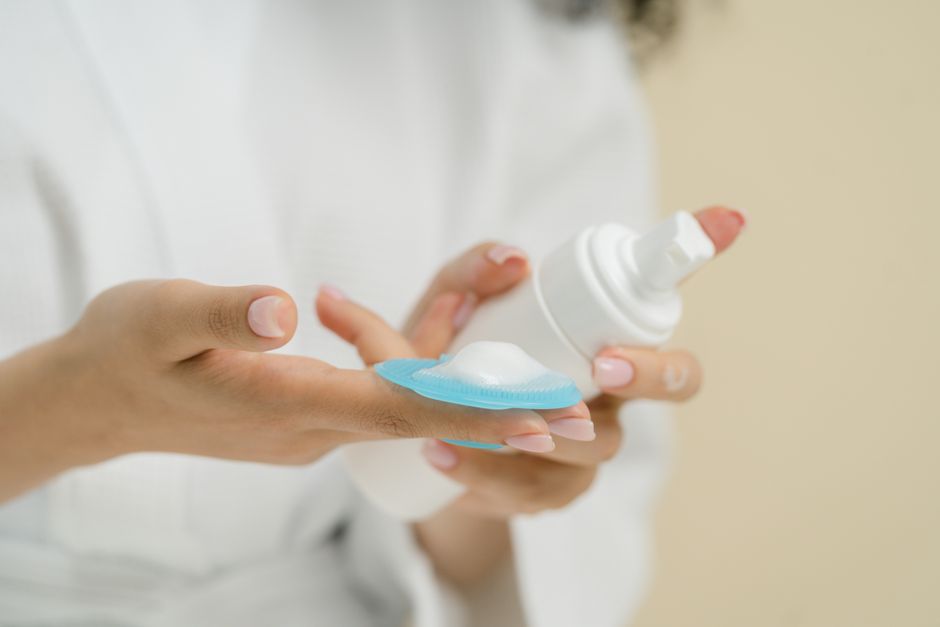 A person's hands holding a tube of gentle cream cleanser, emphasizing the importance of mild products for sensitive skin.