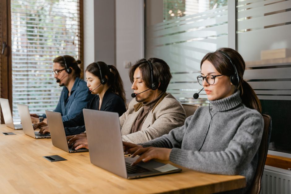 A group of diverse professionals in a modern office, each focused on their laptops, with an overlay of digital tools and AI icons illustrating productivity.