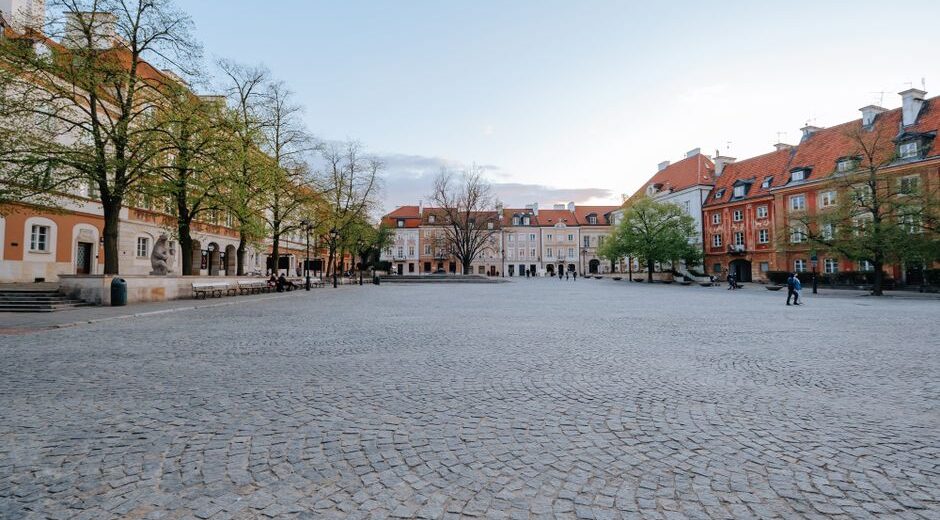 A serene, empty cobblestone street winding through a historic European city, with pastel buildings and blooming flowers in spring, symbolizing fewer crowds.