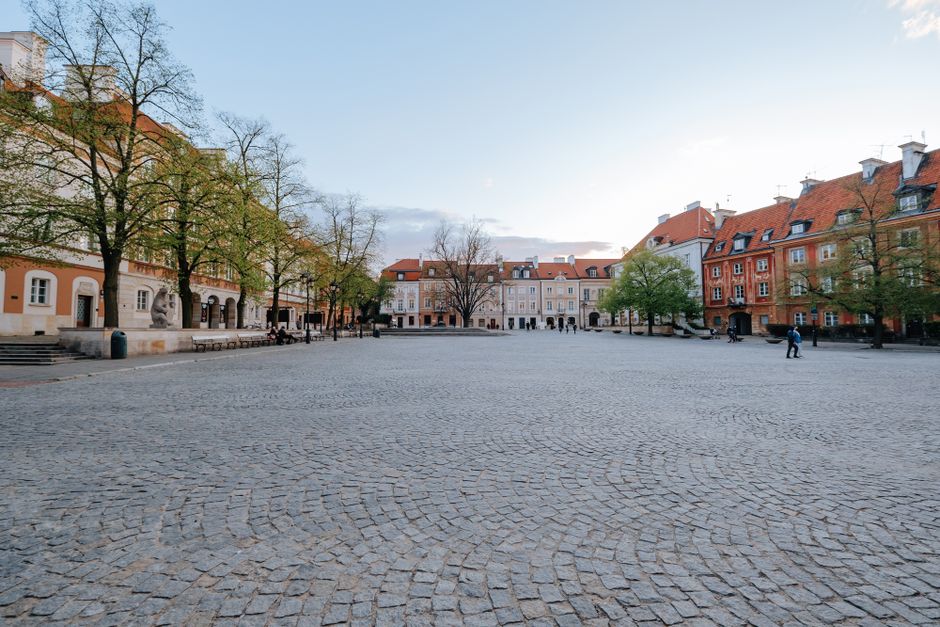A serene, empty cobblestone street winding through a historic European city, with pastel buildings and blooming flowers in spring, symbolizing fewer crowds.