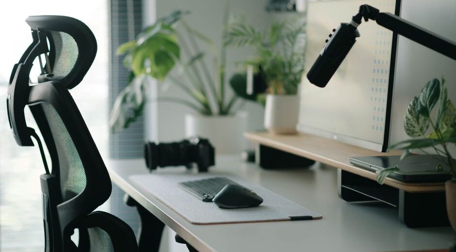 A well-organized home office desk with multiple monitors, ergonomic keyboard, mouse, and smart light, illustrating a productive workspace.