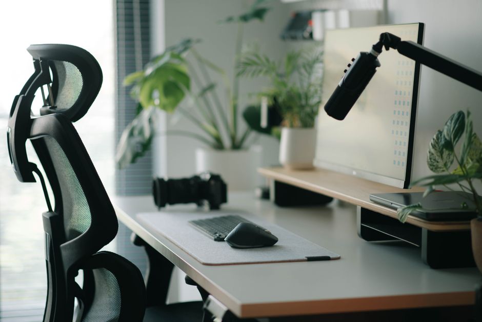 A well-organized home office desk with multiple monitors, ergonomic keyboard, mouse, and smart light, illustrating a productive workspace.