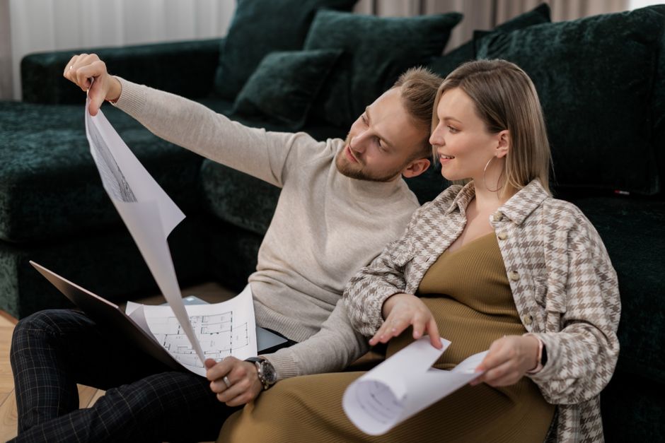 A family, including two adults and a child, sitting around a table, looking at architectural drawings and samples for home upgrades, smiling and engaged.
