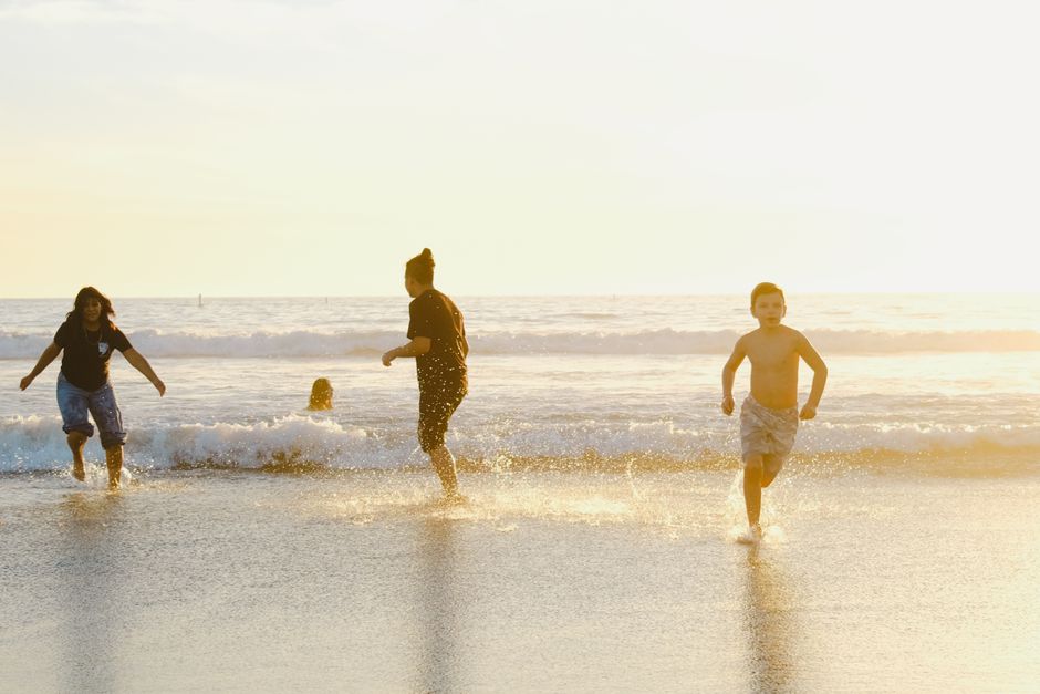 A diverse family laughing and playing on a sunny beach, representing the joy and peace of mind travel insurance provides for worry-free vacations.