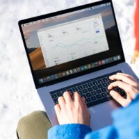 A freelancer in a modern office setting using a laptop, displaying a CRM dashboard with contact and sales pipeline information.