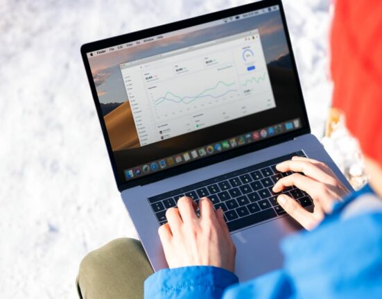 A freelancer in a modern office setting using a laptop, displaying a CRM dashboard with contact and sales pipeline information.