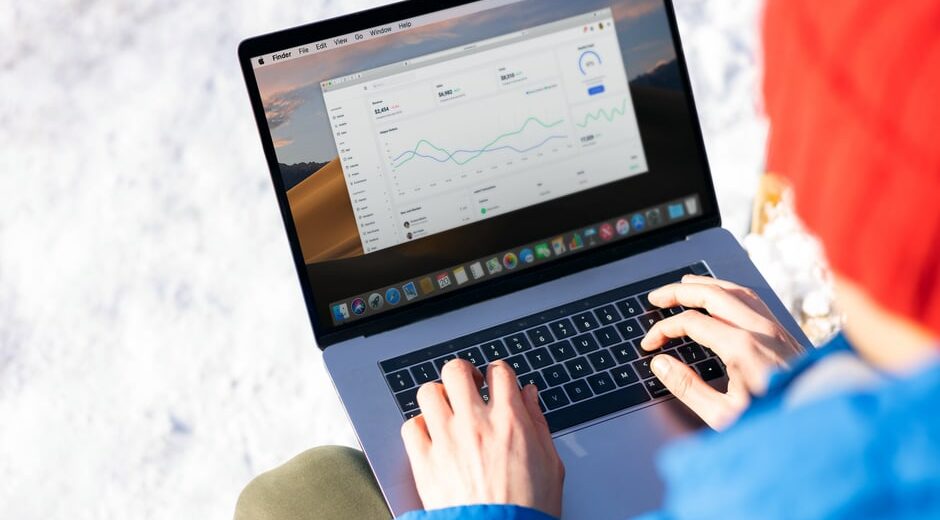 A freelancer in a modern office setting using a laptop, displaying a CRM dashboard with contact and sales pipeline information.