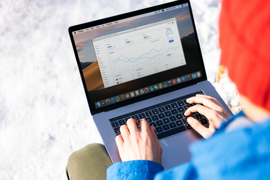 A freelancer in a modern office setting using a laptop, displaying a CRM dashboard with contact and sales pipeline information.