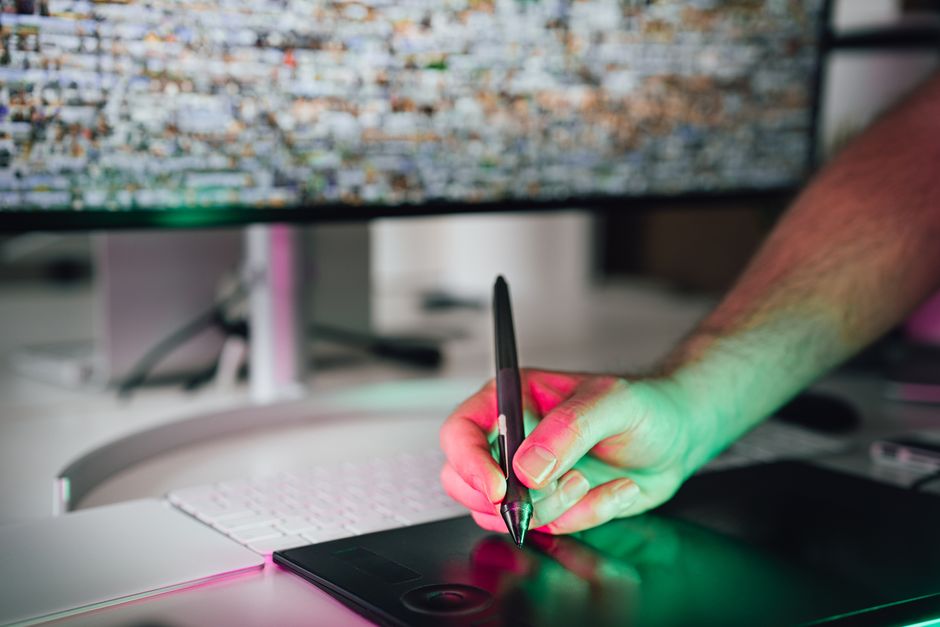 A designer working on a high-resolution monitor, carefully adjusting colours in a graphic design application.
