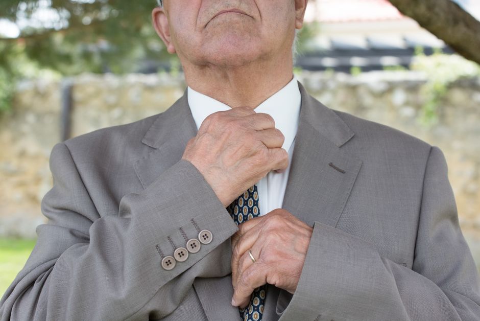 A man standing on a European street, adjusting his navy blazer over a fine-gauge sweater, illustrating effective men's fashion layering for comfort and style.