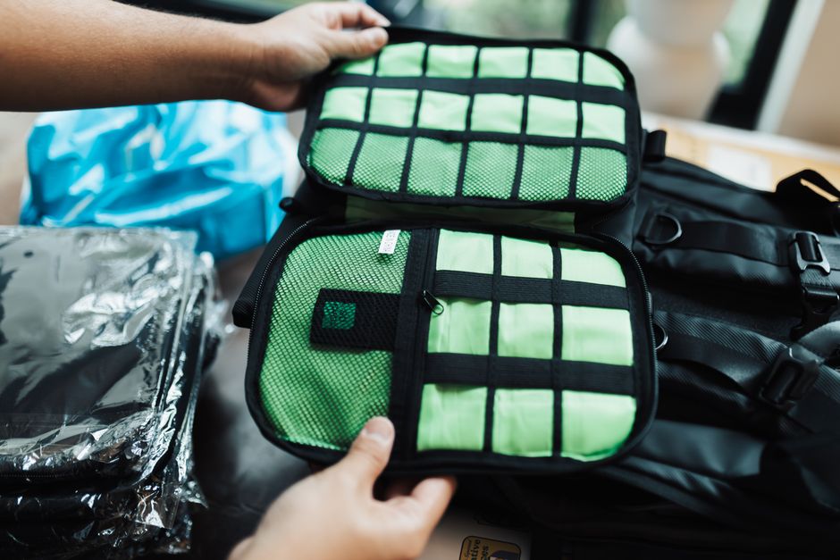 A person utilizing packing cubes to organize clothing and essentials inside a travel backpack, highlighting smart internal organization and laptop protection.
