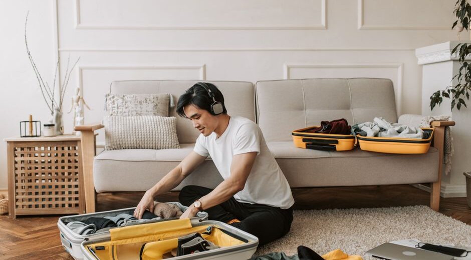 A man carefully folding clothes and placing them into a suitcase, showing a thoughtful packing process for travel.