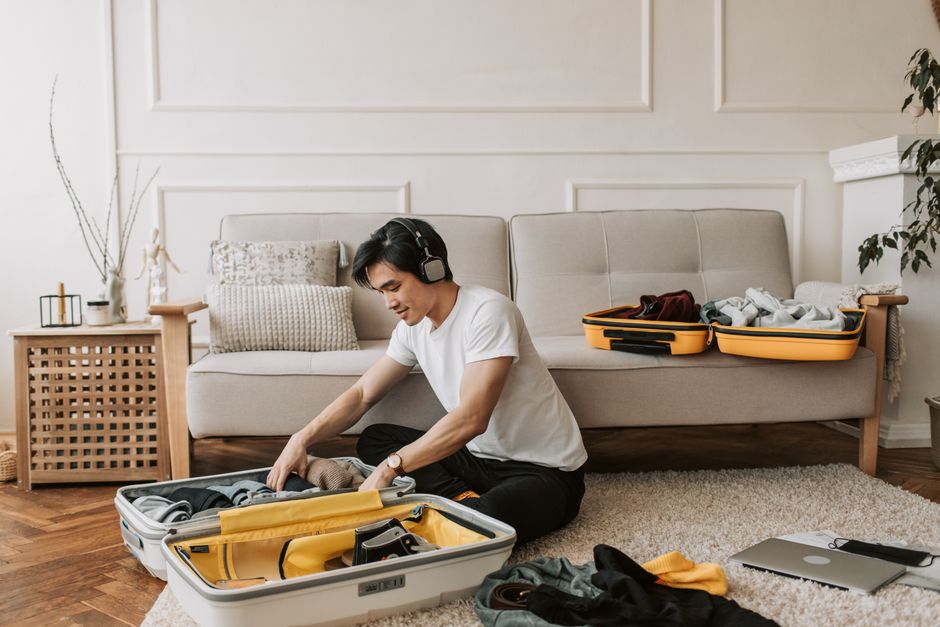 A man carefully folding clothes and placing them into a suitcase, showing a thoughtful packing process for travel.