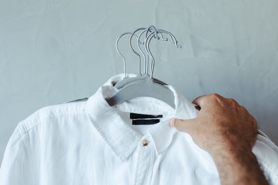 A stylish man standing in front of a neatly organized, minimalist closet, contemplating his outfit for the day, showcasing a practical capsule wardrobe.