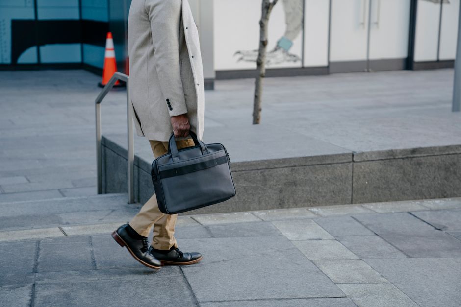 A professional man in a suit walking purposefully on a city street, showcasing his polished black leather office shoes.