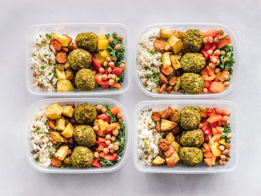 A selection of neatly arranged meal prep containers filled with healthy vegetarian components like cooked quinoa, chopped vegetables, and lentil curry, ready for the week.