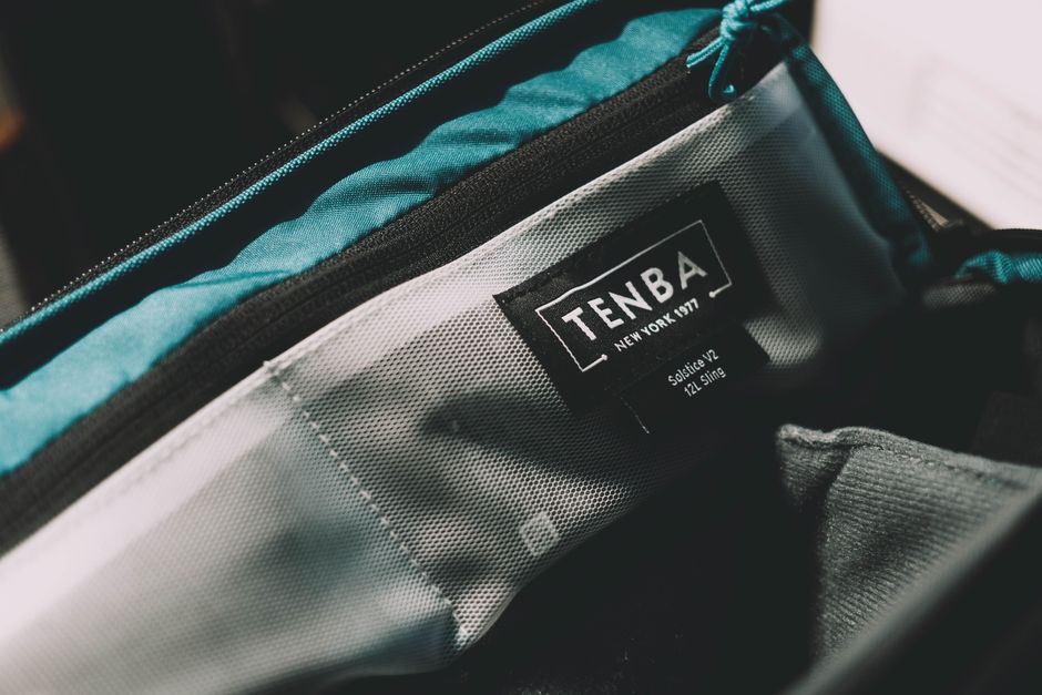 An organized travel bag, possibly a carry-on or backpack, open to show a laptop compartment, smaller pockets, and travel essentials.