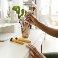 A beautifully organized vanity desk with makeup brushes in clear holders and skincare bottles neatly lined up, showing efficient beauty essentials storage.