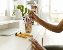 A beautifully organized vanity desk with makeup brushes in clear holders and skincare bottles neatly lined up, showing efficient beauty essentials storage.