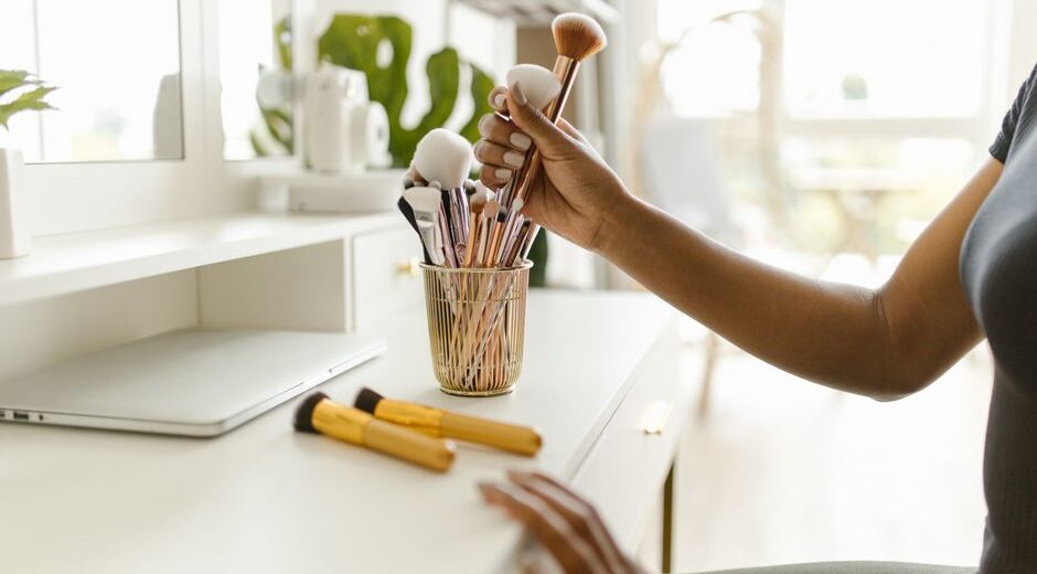 A beautifully organized vanity desk with makeup brushes in clear holders and skincare bottles neatly lined up, showing efficient beauty essentials storage.