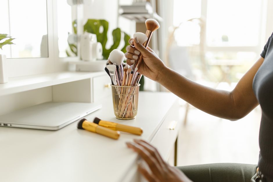 A beautifully organized vanity desk with makeup brushes in clear holders and skincare bottles neatly lined up, showing efficient beauty essentials storage.