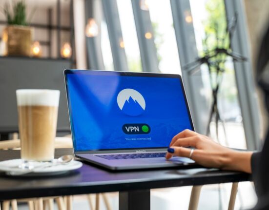 Person using a laptop at a cafe with an open public Wi-Fi connection, illustrating the need for a VPN for privacy and travel.