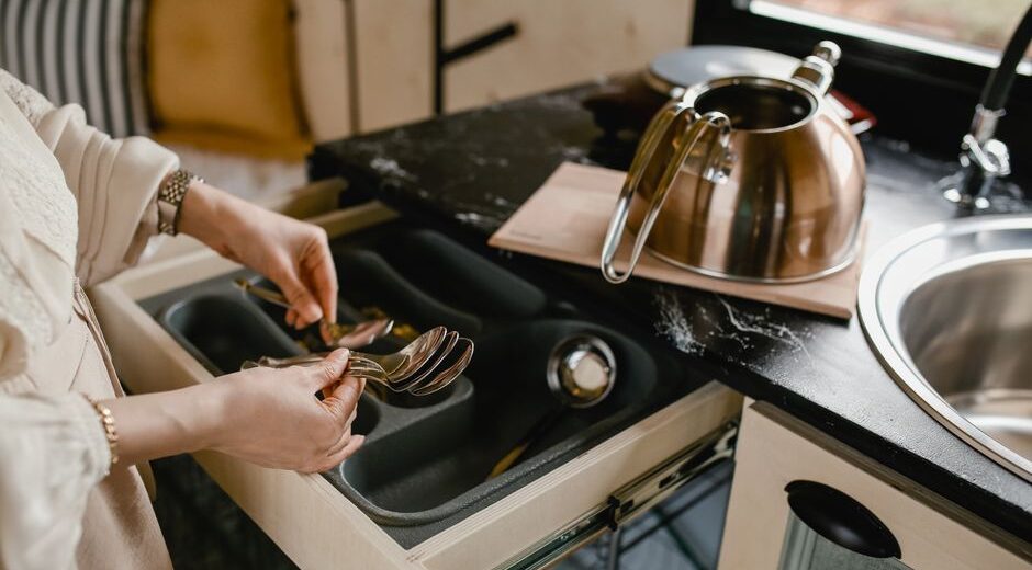 A person neatly arranging kitchen utensils in a bamboo drawer organizer, demonstrating home organization.