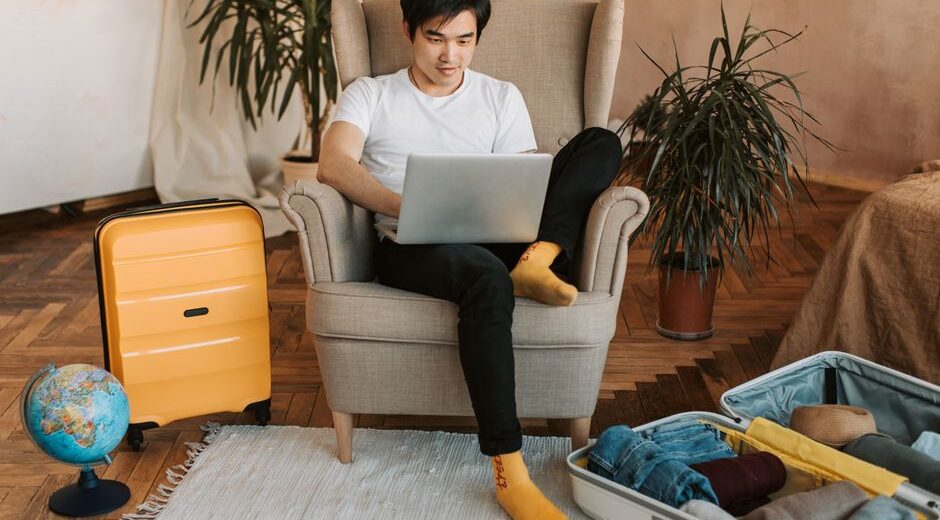 A person with a laptop open, looking at a map and a notebook, surrounded by travel guides and a cup of coffee, signifying meticulous planning for a trip.