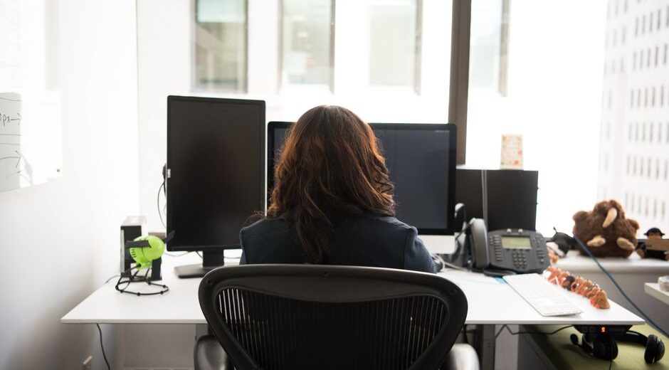 A person connecting a laptop to a large external monitor on a tidy home office desk.