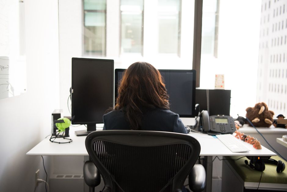 A person connecting a laptop to a large external monitor on a tidy home office desk.