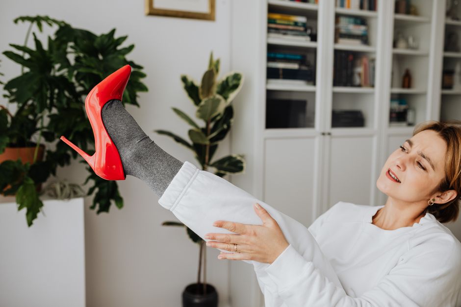 A person sitting on a rug, trying on a new pair of walking shoes received from an online order, checking for comfort and fit.