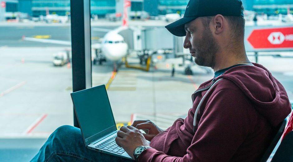 Traveler on laptop at airport gate, connecting to public Wi-Fi.