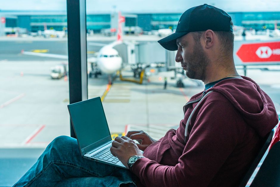 Traveler on laptop at airport gate, connecting to public Wi-Fi.