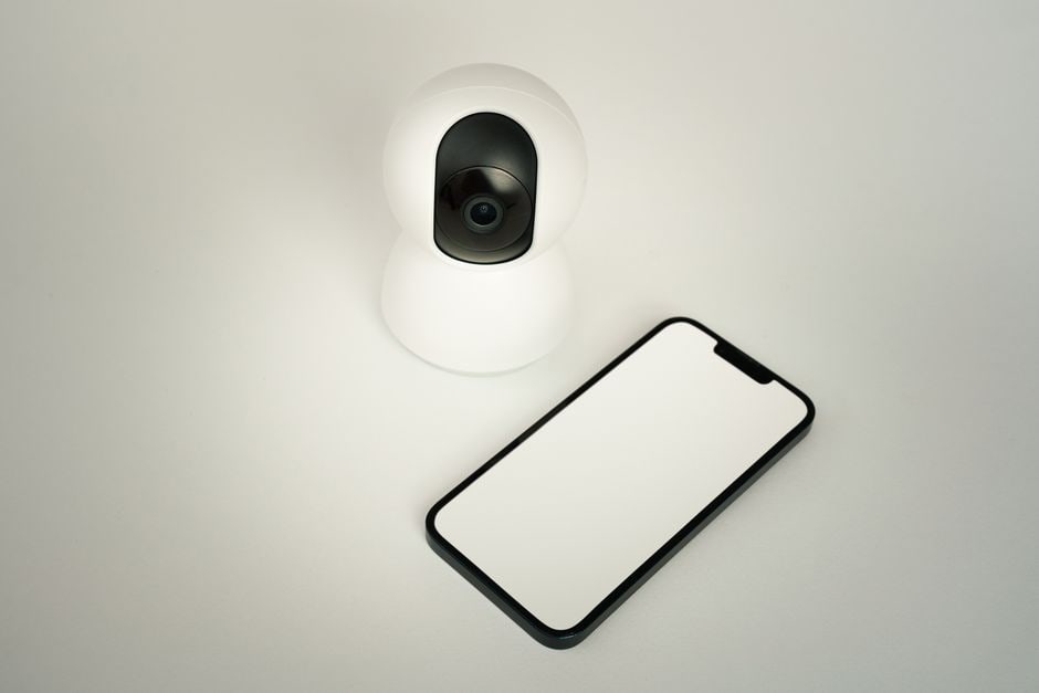 A smartphone screen showing a live feed from a smart security camera, with a person checking their home remotely, highlighting enhanced security.