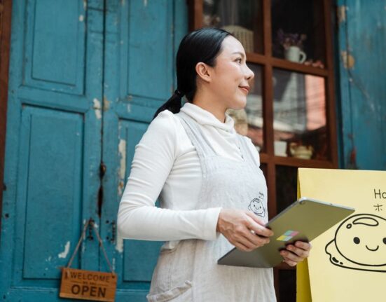 A small business owner uses a tablet to review CRM data, showing charts and customer profiles, illustrating efficient management.