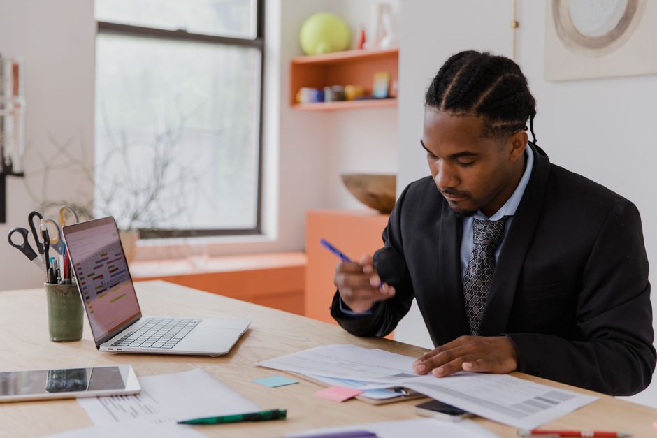 A small business owner in a casual office setting reviewing a visual sales pipeline on a tablet, showing different stages of deals.